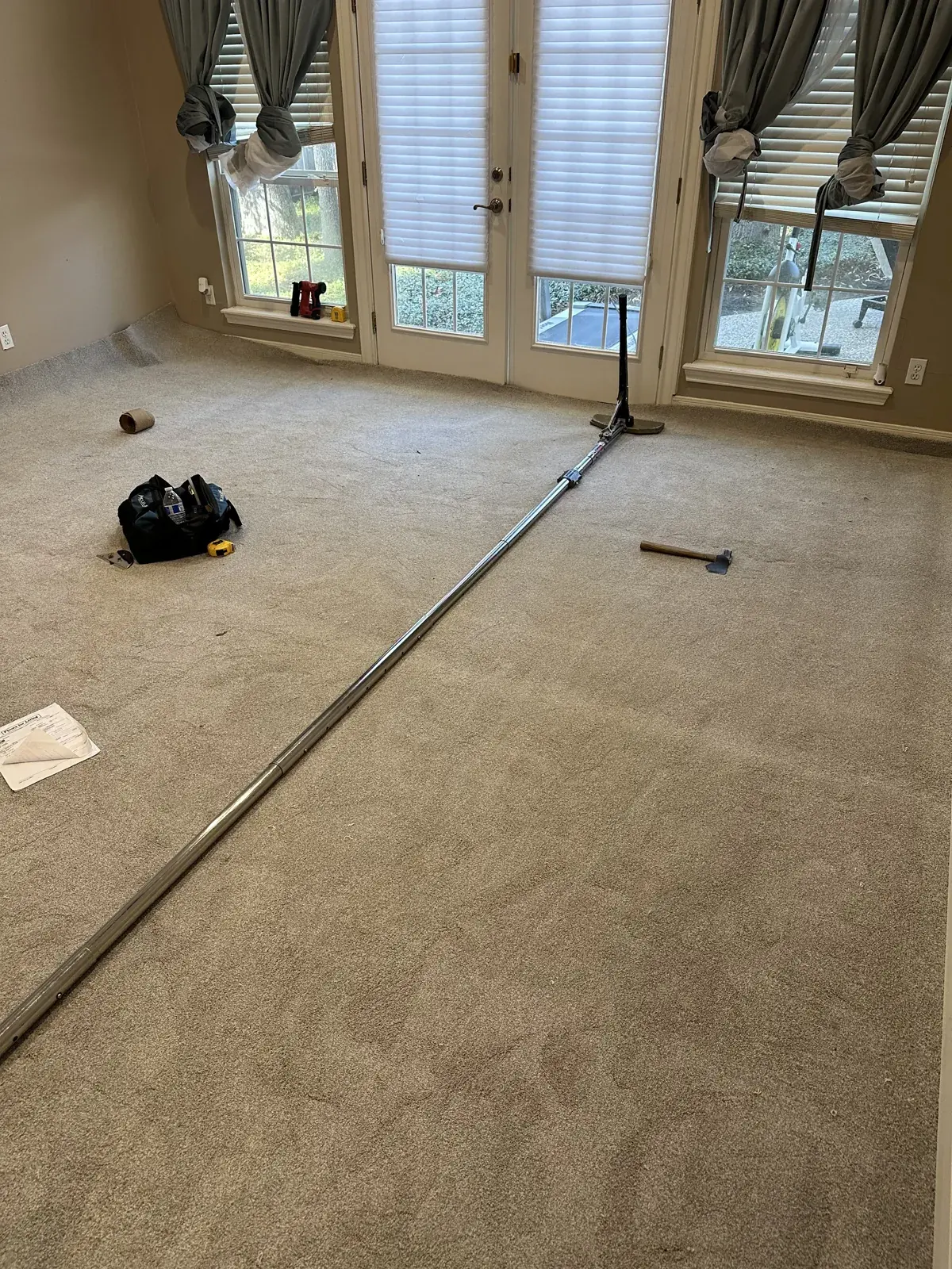 Power stretcher set up across a living room to restretch carpet in Houston